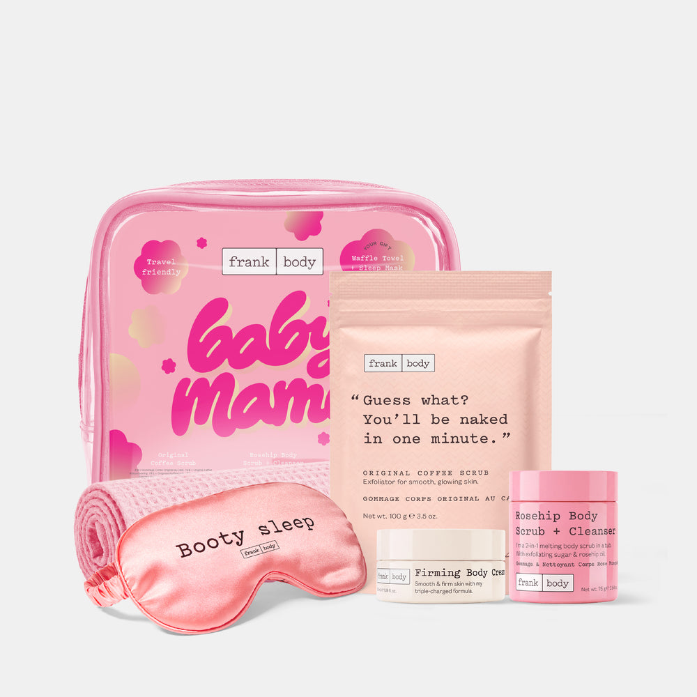 The frank body Baby Mama Kit with the coffee scrub sachet, firming body cream, rosehip scrub tub, pink bag, waffle towel and Booty sleep eye mask on white.