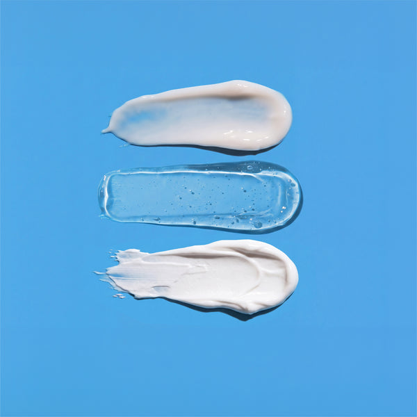 Three swatches from the frank body Thirst Busters Kit on a blue background: a pearly wash, a clear serum gel and a thick white cream.