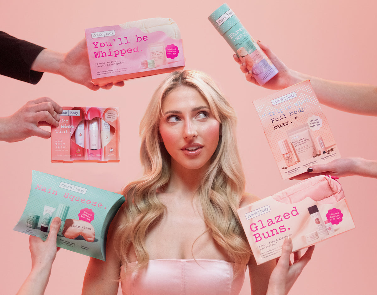 Blonde model surrounded by hands holding up frank body holiday gift sets, including You'll Be Whipped, Main Squeeze, Triple Shot and Glazed Buns.